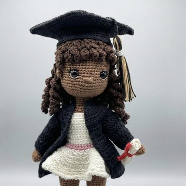Gradgirl, a crocheted doll in a graduation cap and gown holding a diploma
