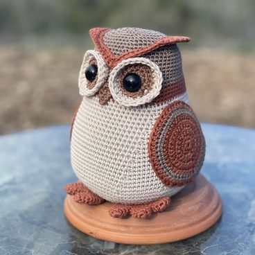 Rusty the Wood Owl, a crocheted owl in cream and rust sitting on a wooden base